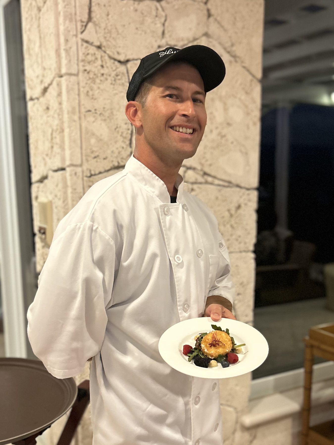 Chef Zeno in his chef jacket presenting a plated dish